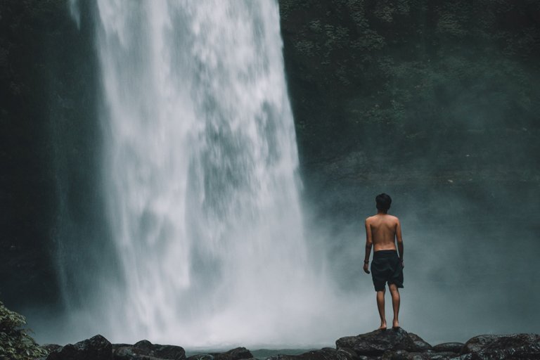 Hombre listo para bañarse en la cascada Nungnung, Bali