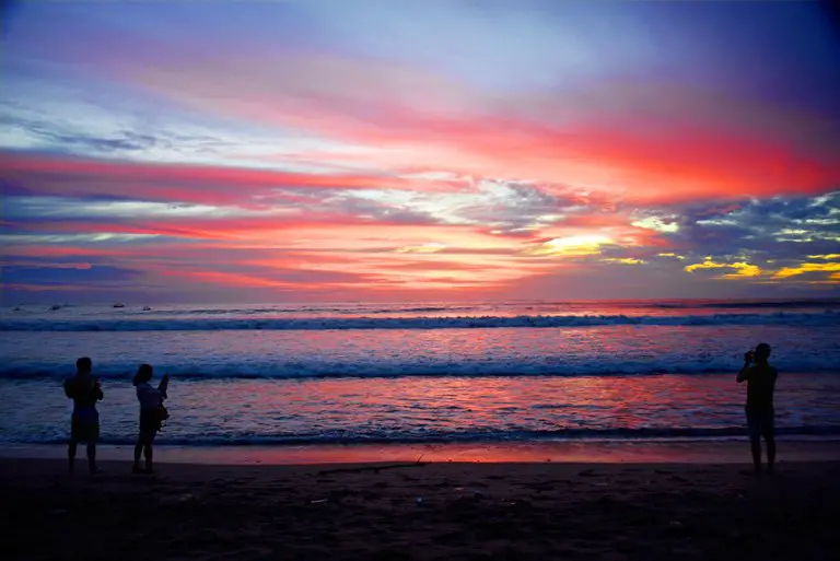 Varias personas disfrutando del atardecer en la playa de Kuta, Bali